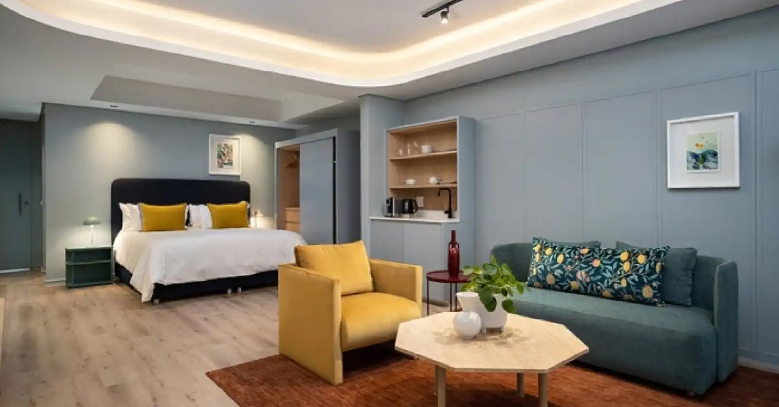 Spacious hotel suite with a king-size bed, kitchenette and lounge area