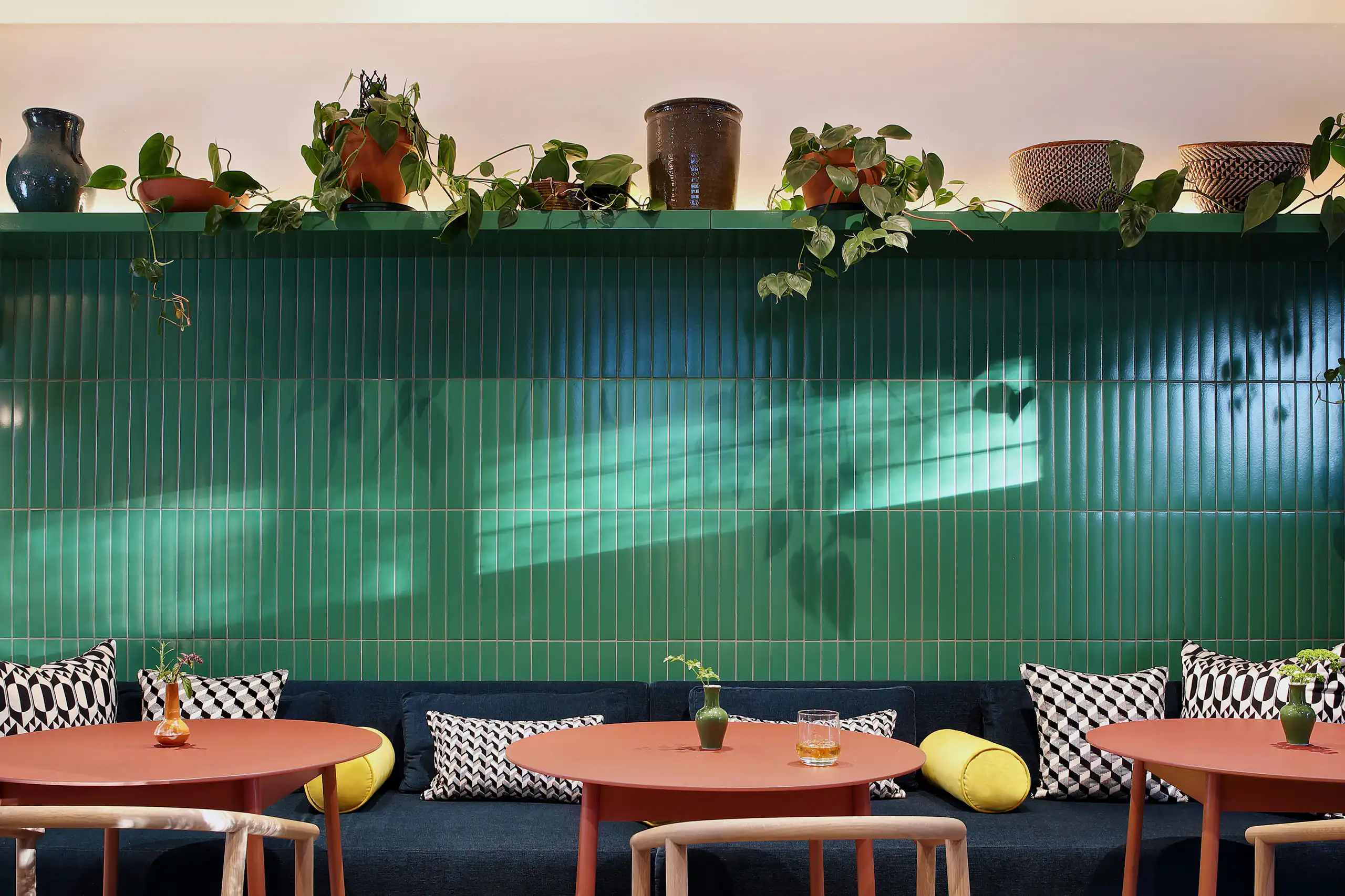 Colourful hotel dining lounge with a green tiled wall and indoor plants