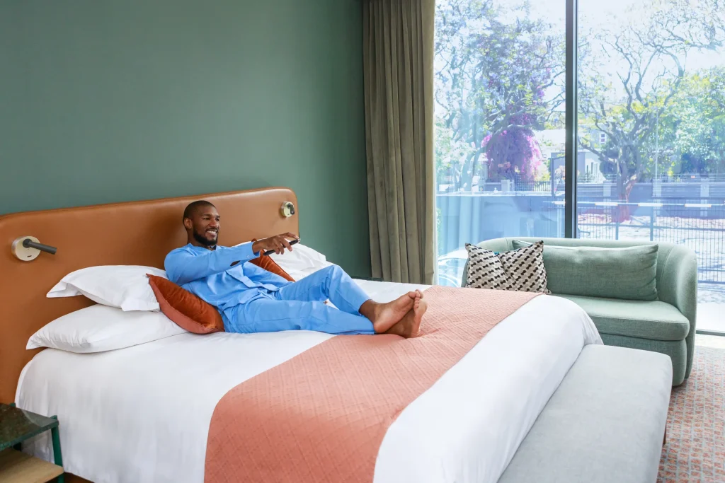 Guest relaxing on a king-size bed at Home Suite Hotels Rosebank in Johannesburg