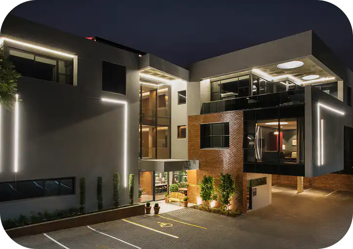Exterior of Home Suite Hotels Rosebank lit up at night, Johannesburg
