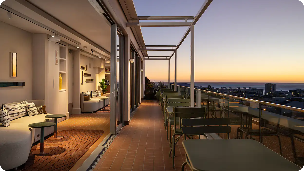 Rooftop terrace at Home Suite Hotels Sea Point at dusk, with lounge seating and views over Cape Town's Atlantic Seaboard