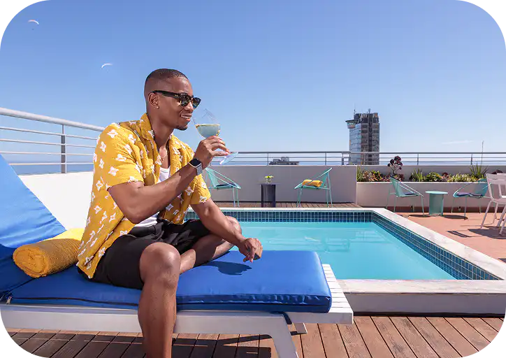 Guest relaxing with a cocktail by the rooftop pool at Home Suite Hotels Sea Point